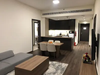 a living room with a couch and a table and a kitchen at Azur Regency Hotel Apartments in Dubai