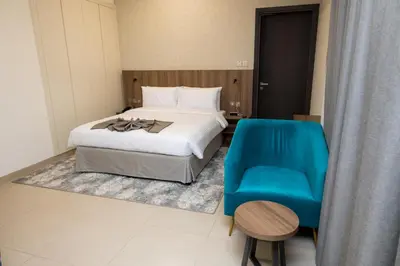 a bedroom with a bed and a blue chair at Azur Regency Hotel Apartments in Dubai