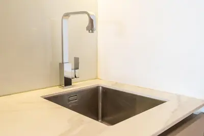 a stainless steel kitchen sink with a faucet at Unique loft with smart working station in Dubai