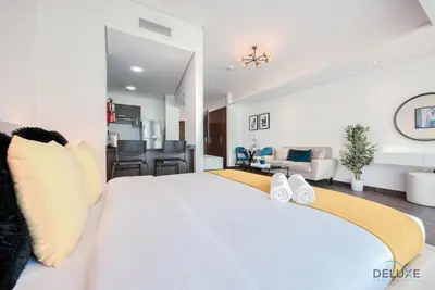 a bedroom with a large white bed with shoes on it at Cozy Studio at The Matrix Sports City by Deluxe Holiday Homes in Dubai