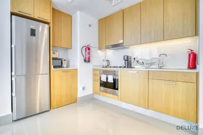 a kitchen with wooden cabinets and a stainless steel refrigerator at Extravagant 1BR at Opera Grand Downtown Dubai by Deluxe Holiday Homes in Dubai
