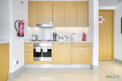 a kitchen with wooden cabinets and a stove at Extravagant 1BR at Opera Grand Downtown Dubai by Deluxe Holiday Homes in Dubai