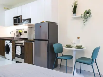 a kitchen with a refrigerator and a table with chairs at Elite LUX Holiday Homes - Modern Style Studio Superior Facilities in Arjan Dubai in Dubai