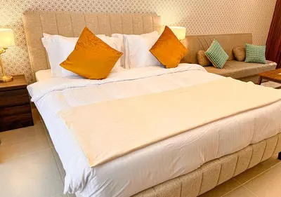 a large bed with orange and white pillows on it at Cosmos Living Modern Studio Near Dubai Marina in Dubai