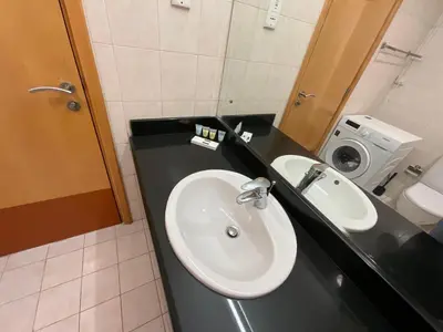 a bathroom with a sink and a washing machine at Discovery Gardens Haven Studios in Dubai