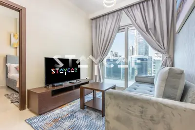 a living room with a couch and a tv and a window at Staycae Holiday Homes - Reva in Dubai