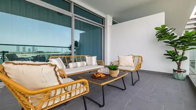 a patio with wicker chairs and a table on a balcony at Hashtag Holiday Home - Luxury 2BDR Apartment on The Palm Azure Residences in Dubai