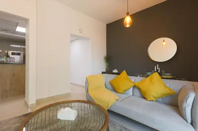 a living room with a gray couch with yellow pillows at Spacious 1BR with full Marina View in Dubai