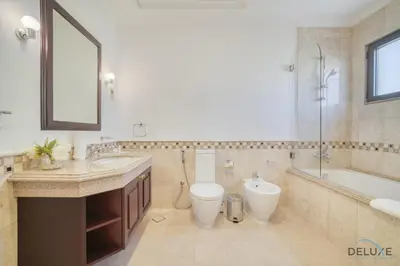 a bathroom with a toilet and a tub and a sink at Signature 6BR Villa with Assistant Room and Private Pool in Frond F Palm Jumeirah by Deluxe Holiday Homes in Dubai