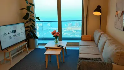 a living room with a couch and a tv and a table at Exquisite, luxe 1BD Apartment, Unparalleled Sea Views, Prime Dubai Marina Location & Full Kitchen by 