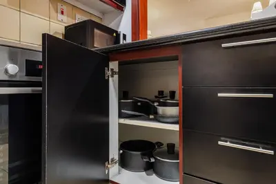 a kitchen with black cabinets and pots and pans at Beautiful 2BR & 4BR Apartments on JBR Beach, Walking Distance to Bluewaters Island - By Sunkissed Holiday Homes in Dubai