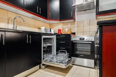 a kitchen with black cabinets and a dishwasher at Beautiful 2BR & 4BR Apartments on JBR Beach, Walking Distance to Bluewaters Island - By Sunkissed Holiday Homes in Dubai