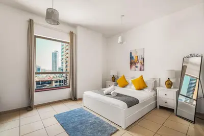 a white bedroom with a bed and a window at Beautiful 2BR & 4BR Apartments on JBR Beach, Walking Distance to Bluewaters Island - By Sunkissed Holiday Homes in Dubai