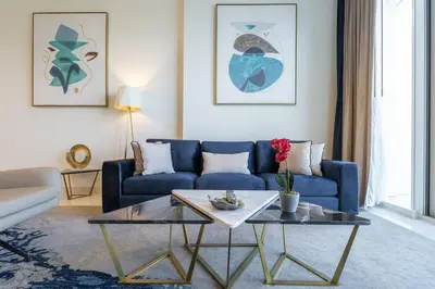 a living room with a blue couch and a table at Exquisite Apartment Minutes Away from the Beach in Dubai