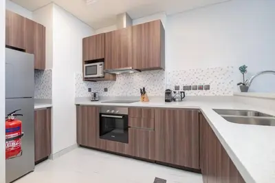 a kitchen with wooden cabinets and stainless steel appliances at Exquisite Apartment Minutes Away from the Beach in Dubai