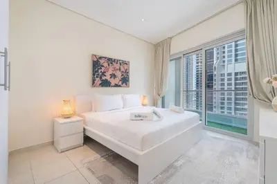 a bedroom with a white bed and a large window at Charming Apartment in Central Dubai Marina in Dubai