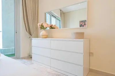 a white dresser with a mirror on top of it at Charming Apartment in Central Dubai Marina in Dubai
