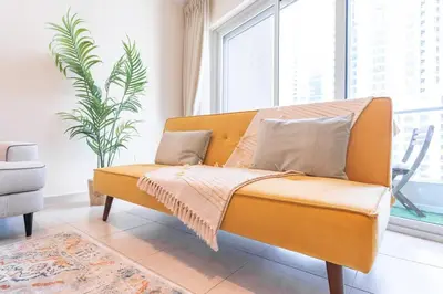 a yellow couch in a room with a plant at Charming Apartment in Central Dubai Marina in Dubai