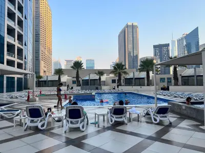 a pool on the roof of a building with people sitting in chairs at Waterfront Yachts View Studio in Bay Central, Dubai Marina in Dubai
