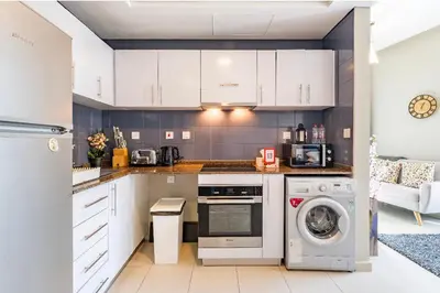 a kitchen with white cabinets and a washer and dryer at Waterfront Yachts View Studio in Bay Central, Dubai Marina in Dubai