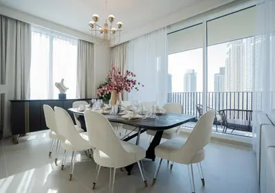 a dining room with a black table and white chairs at Nasma Luxury Stays - Harbour Gate Tower 1 in Dubai