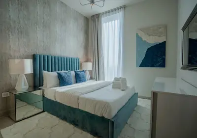 a bedroom with a bed with a blue headboard and a window at Nasma Luxury Stays - Harbour Gate Tower 1 in Dubai