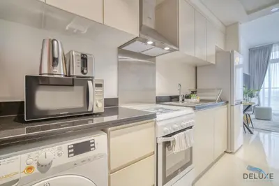 a kitchen with a microwave and a dishwasher at Calm Studio at Carson C DAMAC Hills Dubailand by Deluxe Holiday Homes in Dubai