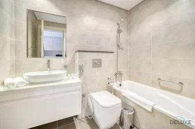 a bathroom with a sink and a toilet and a tub at Calm Studio at Carson C DAMAC Hills Dubailand by Deluxe Holiday Homes in Dubai