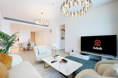 a living room with a tv and a couch and a table at Livbnb - Lush 2BR Suite with Sea and Ain View in Address JBR in Dubai