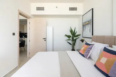 a bedroom with a large white bed with colorful pillows at Frank Porter - Binghatti Avenue in Dubai
