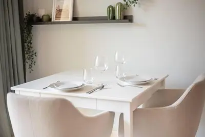 a white table with plates and wine glasses on it at Central studio in The Greens 10min to MetroStation in Dubai