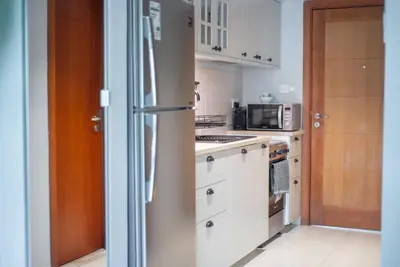 a kitchen with white cabinets and a refrigerator at Central studio in The Greens 10min to MetroStation in Dubai