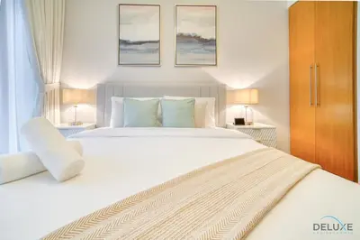 a bedroom with a large white bed and two lamps at Hot Deal Modern 1BR at Iris Blue, Don't Miss Out by Deluxe Holiday Homes in Dubai