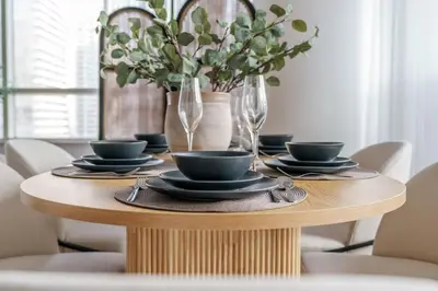 a wooden table with plates and glasses and flowers on it at GuestReady - Bohemian Apt with Marina View in Dubai