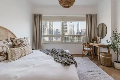 a bedroom with a bed and a desk and a window at GuestReady - Bohemian Apt with Marina View in Dubai