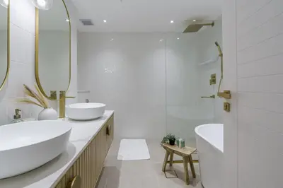 a white bathroom with two sinks and a shower at GuestReady - Bohemian Apt with Marina View in Dubai