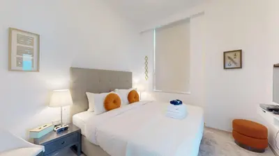 a white bedroom with a large white bed with orange pillows at BR Luxe 1 BDR Apartment w/ Balcony & Sea Views in Dubai