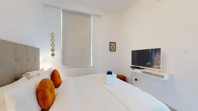 a white bed with orange pillows and a television at BR Luxe 1 BDR Apartment w/ Balcony & Sea Views in Dubai