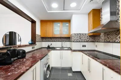 a kitchen with white cabinets and a red counter top at Ultimate Stay 2BR Sea View at JBR Beach Ain Dubai High Floor Luxury Stay in Dubai