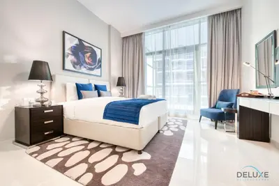 a bedroom with a bed and a desk and a chair at Luxuriant Studio at Golf Promenade 2A DAMAC Hills by Deluxe Holiday Homes in Dubai