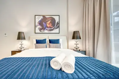 a bedroom with a blue and white bed with two towels at Luxuriant Studio at Golf Promenade 2A DAMAC Hills by Deluxe Holiday Homes in Dubai