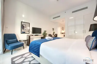 a bedroom with a bed and a desk and a chair at Luxuriant Studio at Golf Promenade 2A DAMAC Hills by Deluxe Holiday Homes in Dubai