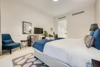 a bedroom with a bed and a chair and a desk at Stunning Studio at Golf Promenade 2A Damac Hills by Deluxe Holiday Homes in Dubai