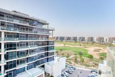 an apartment building with a golf course in the background at Stunning Studio at Golf Promenade 2A Damac Hills by Deluxe Holiday Homes in Dubai