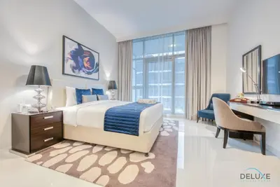 a bedroom with a bed and a desk and a computer at Stunning Studio at Golf Promenade 2A Damac Hills by Deluxe Holiday Homes in Dubai