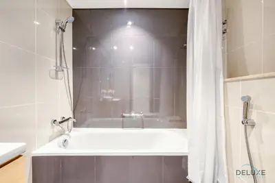 a bathroom with a bath tub with a shower curtain at Stunning Studio at Golf Promenade 2A Damac Hills by Deluxe Holiday Homes in Dubai
