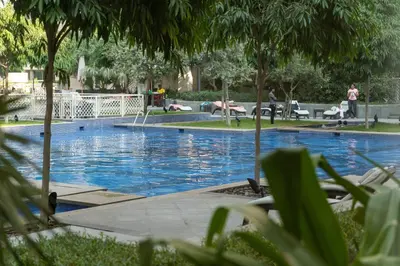 a large swimming pool with people laying on chairs around it at BellaVista - Huge Terrace 1BR Apartment 29 Boulevard Downtown with Burj Khalifa and Fountain Views in Dubai