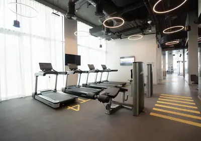a gym with a row of tread machines in a room at Nasma Luxury Stays - The Grand, Dubai Creek Harbour in Dubai