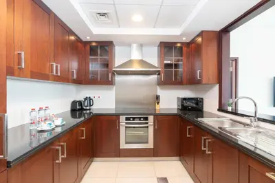 a kitchen with wooden cabinets and a sink at Lux BnB I 29 Burj BLVD I Downtown Views in Dubai