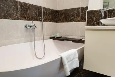 a bathroom with a bath tub and a sink at BellaVista 29 Boulevard 1 Bedroom Apartment with Extra Bedroom Partial Fountain Views in Dubai